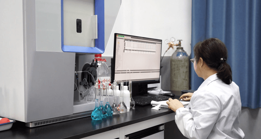 Analytical instrument with computer workstation and volumetric flasks containing sample solutions.