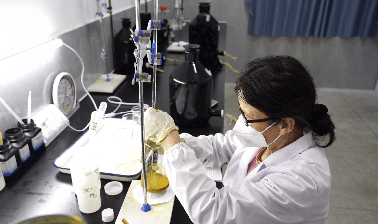 Technician handling reagents and samples at a fume hood with labeled chemical bottles.